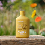 Arber yellow insecticide bottle placed on a wooden surface with blurred garden flowers in the background