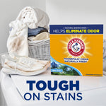 Arm & Hammer Alpine Clean powder detergent box on a laundry surface with shoes and a laundry basket in background