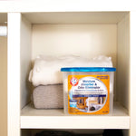 Arm & Hammer moisture absorber tub displayed inside a cubby shelving space next to folded knit blankets