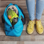 Lifestyle image of an orange Arm & Hammer deodorizer ball inside an open blue gym bag beside yellow sneakers on a wood floor
