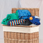 Laundry basket filled with clothes and an orange Arm & Hammer Odor Busterz deodorizer ball resting on top of garments