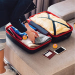 Travel lifestyle photo showing an open suitcase with clothing and two Arm & Hammer orange deodorizer balls placed inside and on the bed