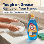 Lifestyle image of hands washing a bowl at a sink with a bottle of Arm & Hammer + OxiClean Ocean Fresh dish soap and sponge nearby.