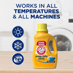 Yellow Arm & Hammer detergent bottle on a wooden surface with icons and text 'Works in all temperatures & all machines'.