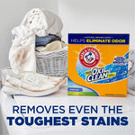 Lifestyle scene showing ARM & HAMMER Plus OxiClean detergent box beside a laundry basket and dirty sneakers
