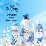 Assortment of Downy Light Ocean Mist products including bottle and rinse with text amplify your freshness on a sky background