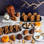 Assortment of Halloween-themed cakes and skull-shaped bakes with a large skull cake and Nordic Ware skull pan in the scene.