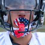 Athlete wearing a football helmet fitted with a red stars-and-stripes Shock Doctor Bolt lip guard mounted on the facemask