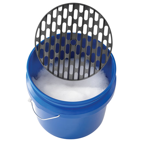 Blue plastic wash bucket filled with suds and a black removable grit guard partially lifted above the rim