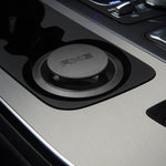 AXE branded round black car air freshener installed in a vehicle cupholder, showing the AXE logo on top.