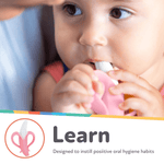 Baby chewing a pink Nuby NanaNubs banana massaging toothbrush with textured silicone tip