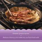 Bacon strips frying in a skillet lined with unbleached parchment demonstrating a grease barrier in use