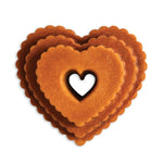 Baked golden heart-shaped tiered cake showing scalloped edges and heart center, isolated on white background