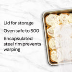 Top-down view of a filled aluminum baking pan with a translucent lid and text callouts listing features on a marble background