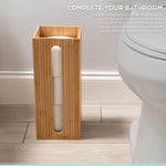 Bamboo square toilet paper reserve placed on a bathroom floor next to a toilet showing stacked rolls visible through front slot