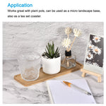 Bamboo rectangular tray used as a small display base holding a glass, a potted plant and a reed diffuser on a tabletop.