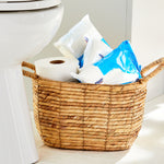 Wicker bathroom basket holding multiple Equate flushable wipes packs and a roll of toilet paper