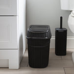 Matte black rattan-style trash can and matching toilet brush set placed on a bathroom floor next to cabinetry and toilet