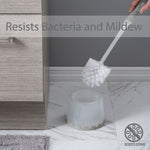 Hand holding Bath Bliss gray-handled toilet brush above frosted holder with overlay text ‘Resists Bacteria and Mildew’