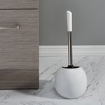White dome toilet brush holder with brush inserted, shown next to gray cabinet on tiled floor