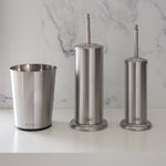 Three-piece stainless steel bathroom set: open waste bin, covered plunger holder, and toilet brush holder on a white surface