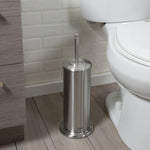 Tall stainless steel covered toilet brush holder placed on a wood-look floor next to a toilet and vanity