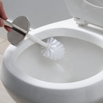 Hand holding a Bath Bliss stainless steel-handled toilet brush scrubbing the inside rim of a white toilet bowl