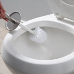 Toilet brush with stainless steel top being used to scrub inside a white toilet bowl