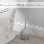 Gray tulip toilet brush placed beside a toilet on a bathroom floor, shown in lifestyle setting
