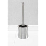 Stainless steel hourglass toilet brush and holder standing upright on a tiled floor against a light textured wall