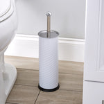 Lifestyle image of Bath Bliss white swirled toilet brush and holder placed on a bathroom floor next to toilet