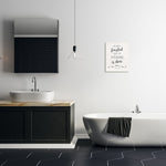 Bathroom scene showing a framed sign on the wall that reads “No job is finished until the paperwork is done” above a freestanding tub