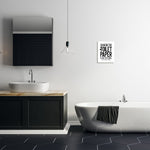 Modern bathroom scene with framed black-and-white 'Changing the Toilet Paper is Not Optional' poster on a white wall above bathtub