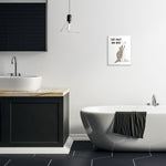 Bathroom interior mockup showing framed raccoon art with 'Take What You Need' hung on a white wall above a freestanding tub