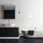 Minimal modern bathroom interior with a framed black-and-white toilet paper patent print hung on the wall above a freestanding tub.