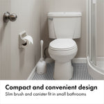 Bathroom scene with a white toilet and the OXO compact toilet brush and canister placed beside it.
