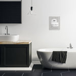 Modern bathroom vignette with freestanding tub, vanity and a small framed toilet-paper phrase print on the wall