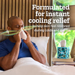 Person blowing their nose in bed with a Kleenex cube box on a bedside table and 'instant cooling relief' text