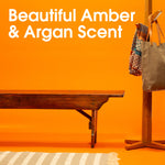 Wood bench and coat rack scene with text ‘Beautiful Amber & Argan Scent’ on an orange studio background