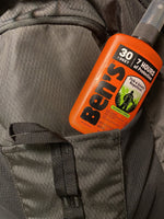 Orange Ben's 30% DEET pump spray bottle tucked into the pocket of a gray backpack, angled view