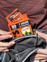 Orange Ben's box of tick & insect repellent wipes with a single packet partially removed, placed near a backpack zipper