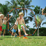 Children playing outdoors around an orange and blue octagon sprinkler spraying water on grass.