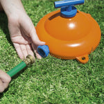 Close-up of an orange dome sprinkler base with a blue hose connector being unscrewed on grass.