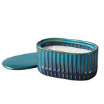 Teal ribbed oval ceramic candle with three unlit wicks and matching lid positioned beside it
