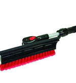 Close-up of red-bristle snow broom head with black plastic housing and red pivot button on a telescoping pole.