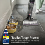 BISSELL multi-surface cleaner cleaning near pet bowls on tiled floor, showing debris and wet cleaning path with bottle graphic.