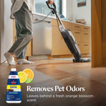 Person pushing a BISSELL upright cleaner across a hardwood kitchen floor, orange blossom citrus graphic and bottle shown.