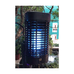 Illuminated Black Flag bug zapper hanging outdoors with blue light visible through safety grille at night