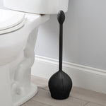 Black tulip toilet brush and base placed on bathroom floor next to a white toilet and baseboard