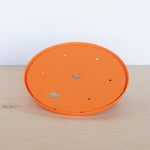 Orange Ups-A-Daisy circular insert photographed on a light wooden surface against a plain backdrop.